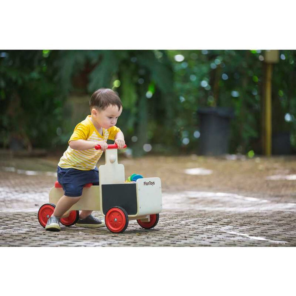 Kid playing PlanToys Delivery Bike