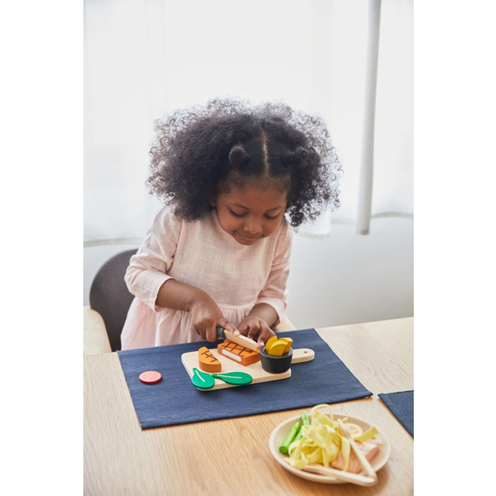 Kid playing PlanToys Steak Set