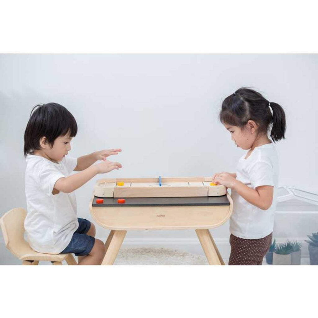 Kid playing PlanToys 2-In-1 Shuffleboard-Game