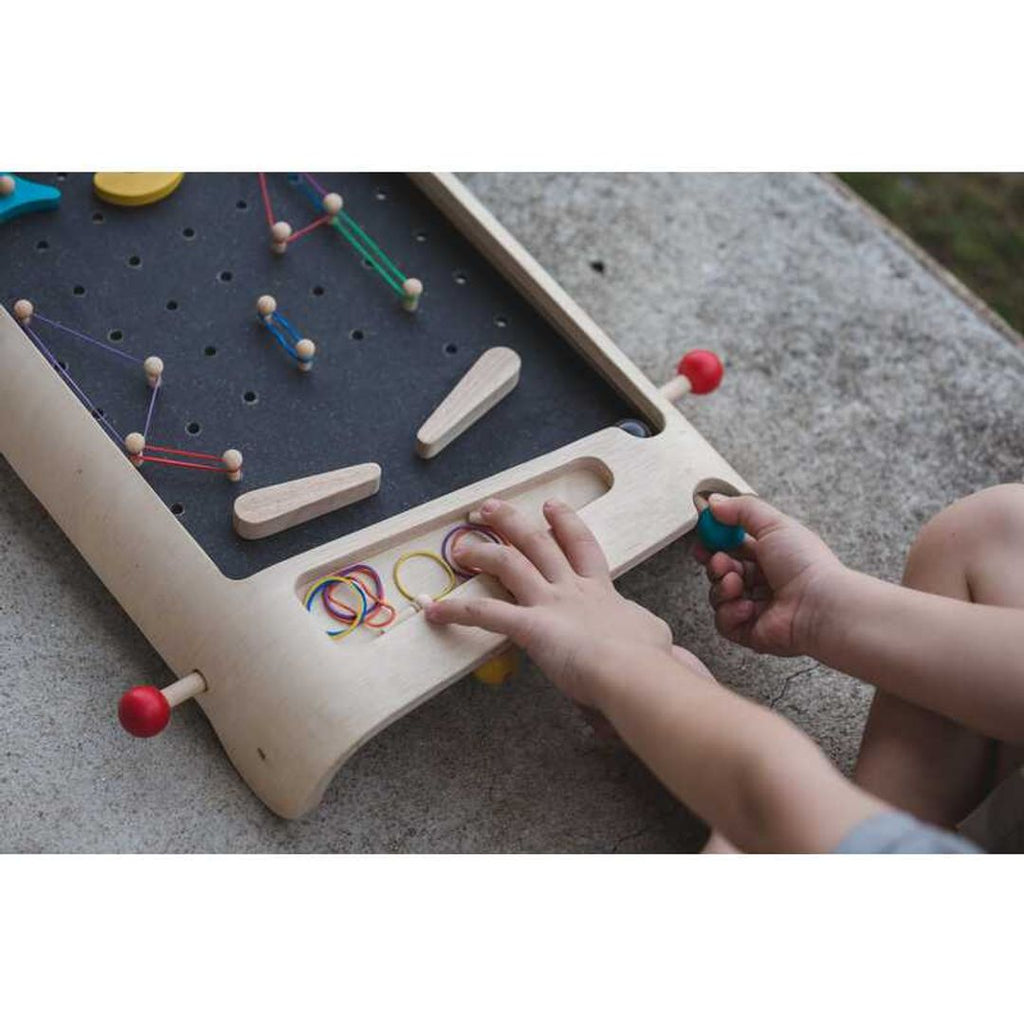 Kid playing PlanToys Pinball