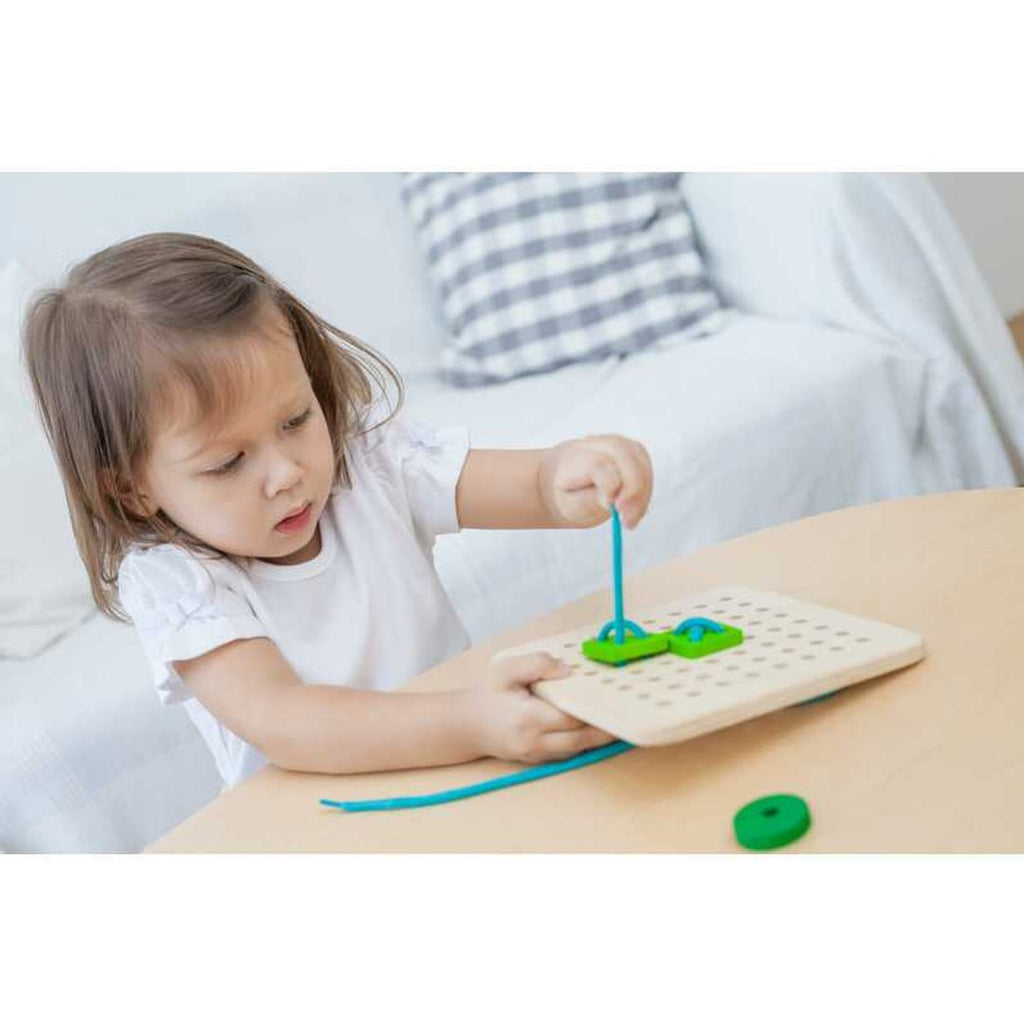 Kid playing PlanToys Lacing Board