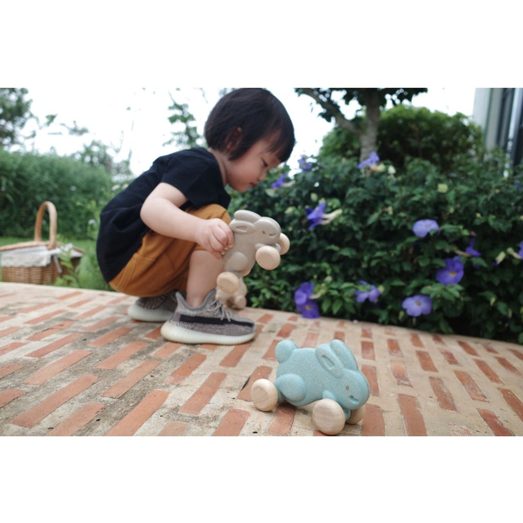 Kid playing PlanToys Push Along Bunny - Grey