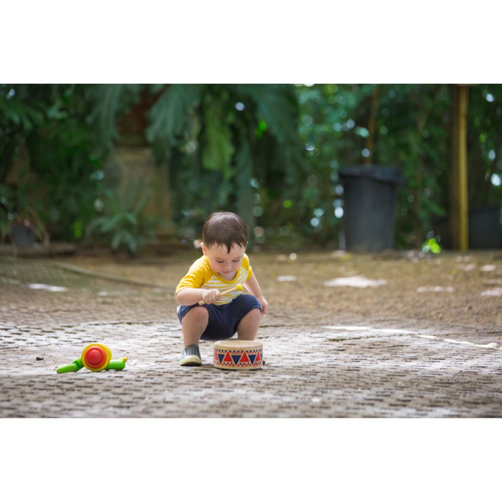 Kid playing PlanToys Solid Drum