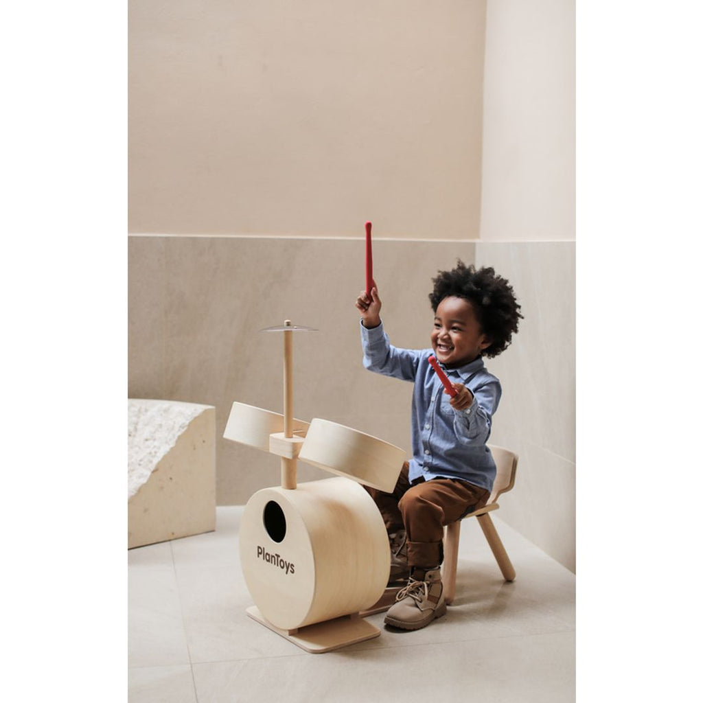 Kid playing PlanToys Drum Set