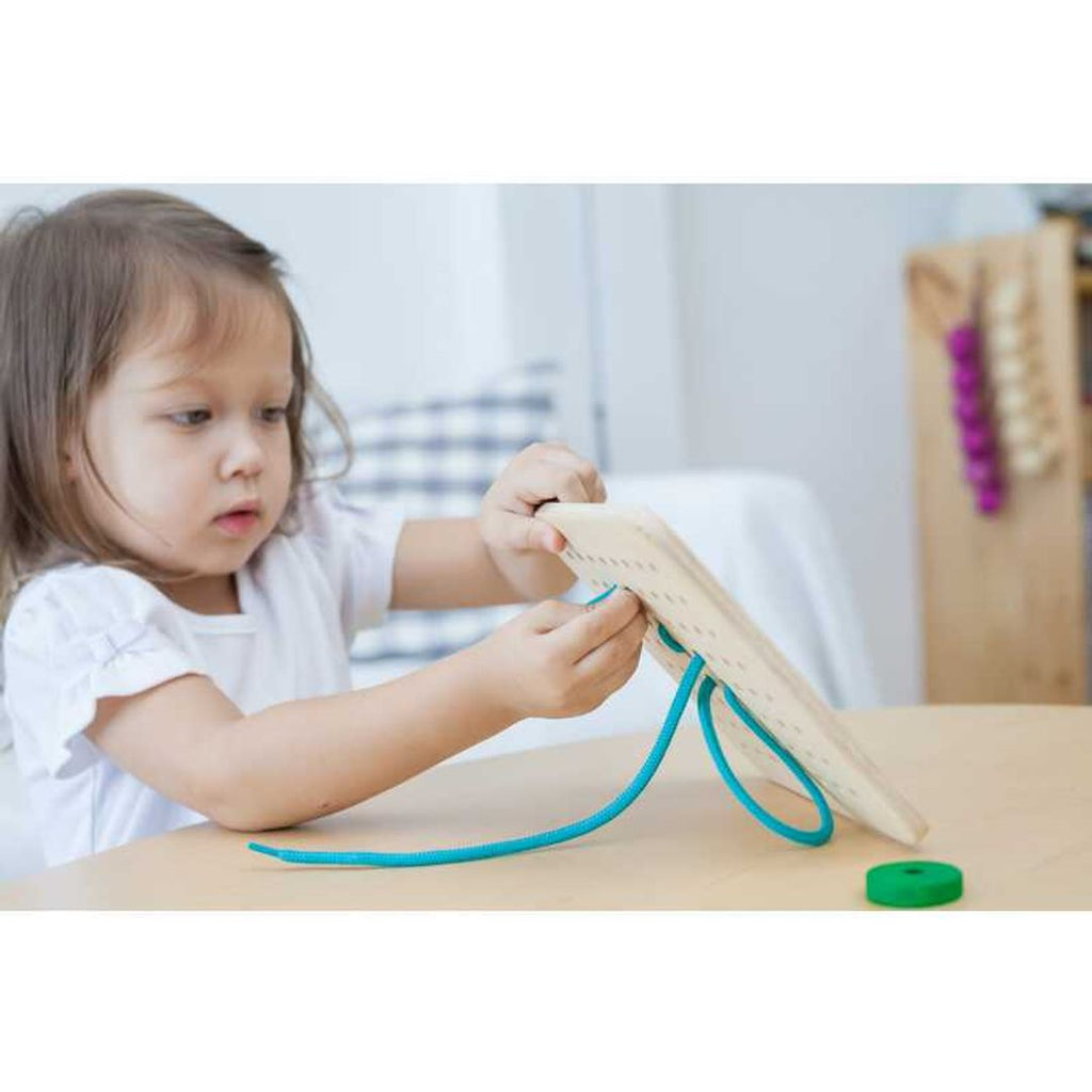 Kid playing PlanToys Lacing Board