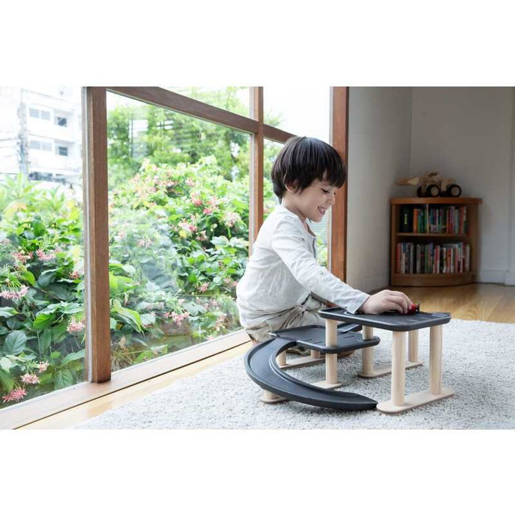 Kid playing PlanToys Race N Play Parking Garage