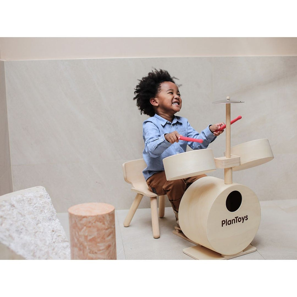 Kid playing PlanToys Drum Set